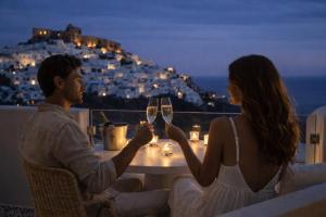 a man and woman sitting at a table with glasses of wine at Atlantic Island Suites in Astypalaia