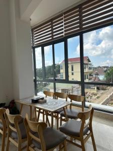 a dining room with a table and chairs and a large window at Tomy Khe Sanh Đà Lạt in Ấp Ða Lợi