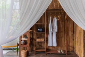 a room with a wooden wall with a curtain at LeLangit Eco Cabin in Sidemen