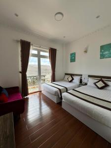 a hotel room with two beds and a window at Tomy Khe Sanh Đà Lạt in Ấp Ða Lợi
