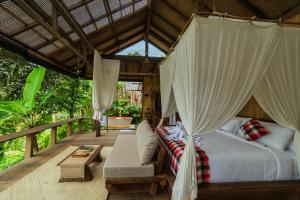 a bedroom with a bed and a couch on a deck at LeLangit Eco Cabin in Sidemen