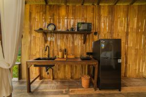 a kitchen with a refrigerator and a wooden wall at LeLangit Eco Cabin in Sidemen