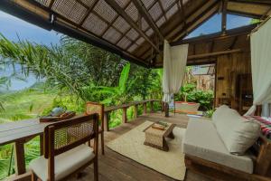 a patio with a table and chairs on a deck at LeLangit Eco Cabin in Sidemen