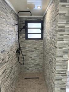 a bathroom with a shower with a brick wall at Villa hibiscus in Sainte-Suzanne +5 photos