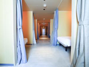 a hallway with blue curtains and a bed in a room at Cabin kutekun in Naka-shibetsu