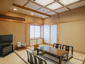 a room with a table and chairs and a television at Kanazawa Kokusai Hotel in Kanazawa