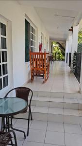 eine Veranda mit einer Bank, einem Tisch und Stühlen in der Unterkunft Hotel Henry Bacalar in Bacalar
