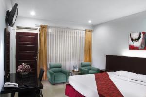 pokój hotelowy z łóżkiem i dwoma krzesłami w obiekcie Rudang Hotel & Resort Berastagi w mieście Berastagi