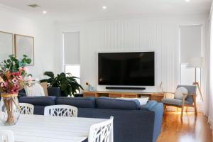 a living room with a blue couch and a tv at Saltwater Cottage in Windang