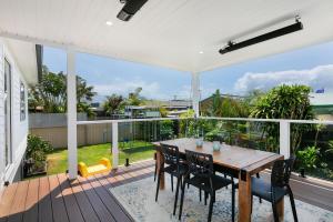 an outdoor deck with a wooden table and chairs at Saltwater Cottage in Windang