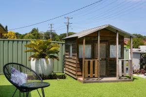 a small shed sitting on the grass with a table and a chair at Saltwater Cottage in Windang