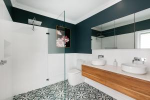 a bathroom with two sinks and a glass shower at Saltwater Cottage in Windang +9 photos