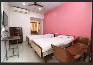 a room with two beds and a desk and a tv at Hotel Gomatgiri in Aurangabad
