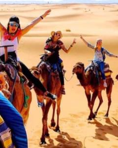 a group of women riding camels in the desert at Authentic Desert Luxury Camp in Merzouga