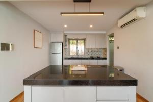 a kitchen with white cabinets and a black counter top at SEA TO SKY Villa - 4 Bedrooms Ocean View in Pulau Nongsa +28 photos