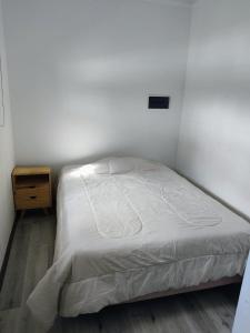 a bedroom with a white bed and a night stand at Quinta Soñada Junin in Junín