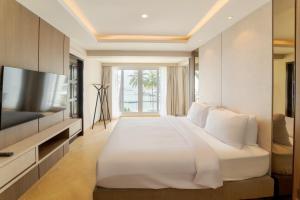 a bedroom with a large white bed and a television at SEA TO SKY Villa - 4 Bedrooms Ocean View in Pulau Nongsa