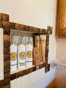 a shelf on a bathroom wall with four bottles of soap at Treetops ella in Ella +143 photos