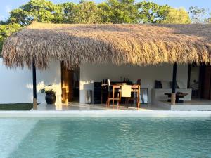 a house with a straw roof next to a swimming pool at Lasa, private villa with private pool in El Nido