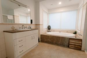 a bathroom with a tub and a sink and a large window at Shambala Estate Cottages in Mount Tamborine