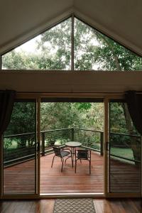 a screened porch with a table and chairs on a deck at Shambala Estate Cottages in Mount Tamborine