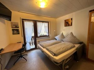 a bedroom with a bed and a desk and a window at Gästehaus im Oberdorf in Erden