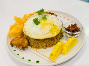 a plate of food with an egg on top of rice at Hotel River Front in Tissamaharama