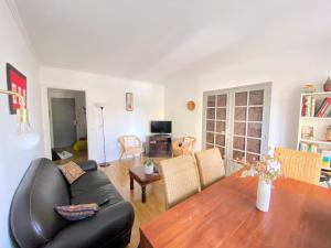 a living room with a table and a black leather couch at Quiet Stay near Paris - Balcony & Private Parking in Châtillon