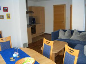 Una sala de estar con una mesa y un sofá azul. en Appartement Granbichler Siegfried, en Längenfeld 8 fotos más
