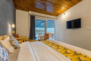 a bedroom with a large bed and a flat screen tv at By the Lake Boho Bhimtal in Bhīm Tāl