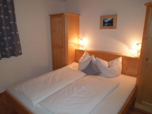una camera da letto con un letto con lenzuola e cuscini bianchi di Haus Panoramablick a Zellberg