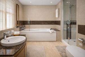 a bathroom with a tub and a sink and a shower at Mascot Houseboats in Srinagar