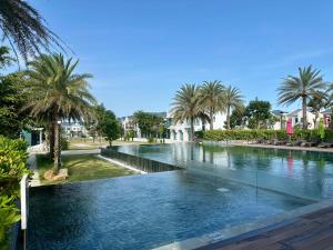 a swimming pool with palm trees in a resort at Bơ Home Novaworld in Phan Thiet