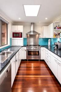 a kitchen with white cabinets and a stainless steel oven at Blue Mountains charm with Spa! in Wentworth Falls