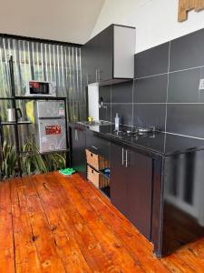 a kitchen with black cabinets and a wooden floor at Twenty ritz cottage in Migori