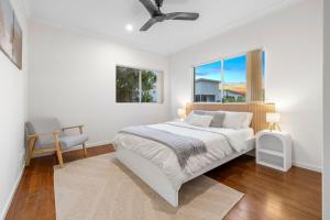 a white bedroom with a bed and a window at Surfmist by the Beach Pet Friendly with Pool in Kingscliff +22 photos