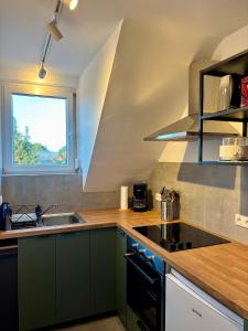a kitchen with green cabinets and a sink and a window at Beehome Wietzendorf in Wietzendorf +3 photos