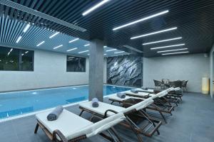 a pool with chaise lounge chairs and a swimming pool at Mercure Tashkent North in Tashkent