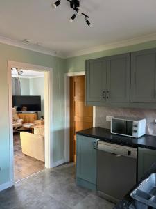 a kitchen with blue cabinets and a microwave at Jerry's lane 3 bed house free parking free wifi in Birmingham +19 photos
