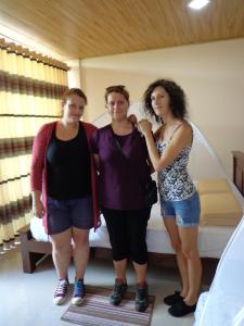 three women standing in front of a bed at Rajarata Reach Resort in Anuradhapura