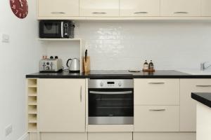 a kitchen with white cabinets and a black stove at 2 Bed beach front apartment with spectacular views overlooking Viking Bay in Broadstairs