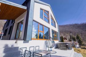 a house with a bench and chairs on a patio at Nessa Chalet in Moara de Pădure