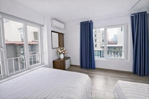 a bedroom with a bed and two windows with blue curtains at Miah Ha Noi Hotel - the best choice in Hà Nội Old Quarter in Hanoi
