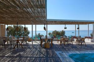 a patio with tables and chairs and the ocean at Kamari Beach Hotel in Kamari