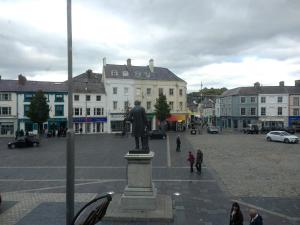 a statue in the middle of a city with buildings at Y Castell in Caernarfon