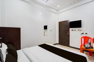 a bedroom with a bed and a door with a television at OYO Hotel O Ayodhya Dham Bus Terminal Formerly Om Palace in Ayodhya