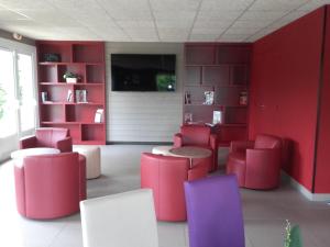 Cette chambre comprend une table et des chaises rouges et violettes. dans l'établissement Campanile Sablé-Sur-Sarthe Vion, à Sablé-sur-Sarthe