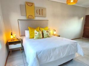 a bedroom with a large white bed with yellow pillows at Nu Oasis guest house in Johannesburg +49 photos