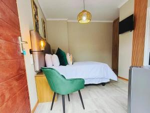 a bedroom with a bed and a green chair at Nu Oasis guest house in Johannesburg