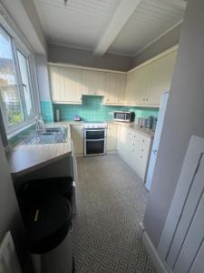 a small kitchen with white cabinets and a sink at PERGOLA Cottage in Melrose